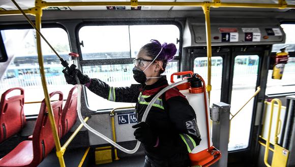 Una trabajadora desinfecta un bus de transporte público en Bogotá. El gobierno de Colombia decretó una cuarentena ante el avance del coronavirus. (AFP / Juan BARRETO).