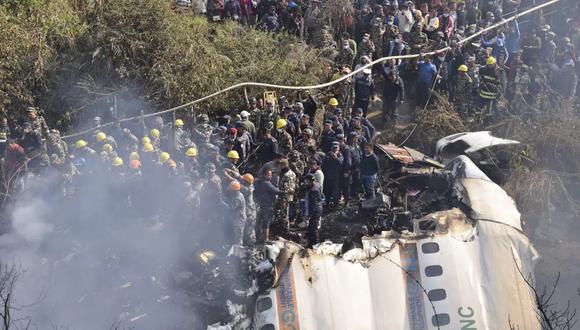 Rescatistas y civiles de Nepal se reúnen alrededor de los restos de un avión de pasajeros que se estrelló en Pokhara, el domingo 15 de enero de 2023. (Foto AP/Krishna Mani Baral).