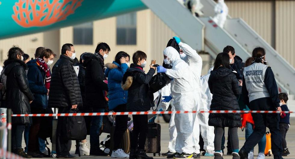 Imagen de archivo de un grupo de pasajeros siendo revisados mientras desembarcan de un avión que transportaba a ciudadanos franceses que salieron de la zona caliente del coronavirus en Wuhan a inicios de febrero. (AFP)
