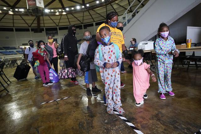 Victoria Nelson y sus hijos Autum Nelson, 2, Shawn Nelson, 7, y Asia Nelson, 6, hacen fila para abordar un autobús para evacuar Lake Charles, Louisiana, el miércoles 26 de agosto de 2020, antes de la llegada del huracán Laura. (Foto AP / Gerald Herbert).