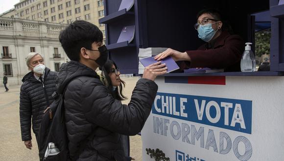 La gente obtiene una copia del borrador de la nueva constitución de Chile frente al Palacio Presidencial de La Moneda en Santiago, el 31 de agosto de 2022. (Foto por Martin BERNETTI / AFP)