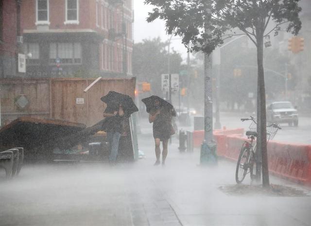 Dos personas caminan bajo el fuerte viento y la lluvia durante la tormenta tropical Isaías en Nueva York. (EFE / EPA / JASON SZENES).