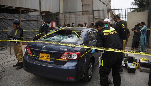 Un grupo de policías vigilan un automóvil usado por presuntos pistoleros mientras los miembros de la Unidad de la Escena del Crimen investigan posibles pruebas. (Asif HASSAN / AFP)
