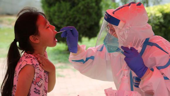 Un trabajador de la salud lleva a cabo una prueba de coronavirus COVID-19 en una niña en un centro de pruebas improvisado en Dalian, en la provincia de Liaoning, noreste de China, el 28 de julio de 2020. (Foto por STR / AFP).