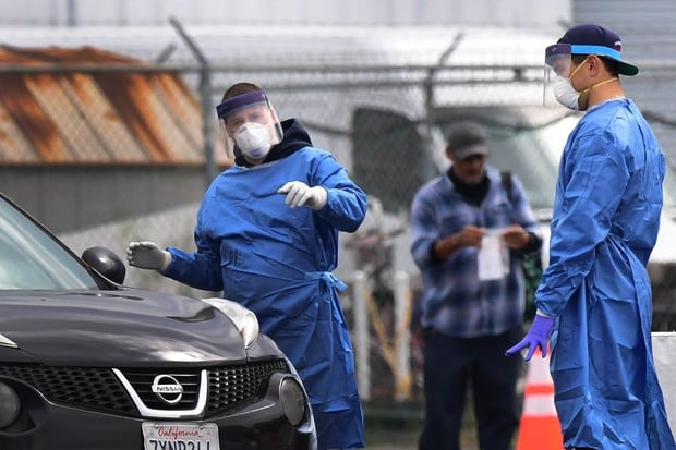 Los trabajadores de la salud ofrecen instrucciones después de dar un kit de prueba de coronavirus a un conductor en el sitio de pruebas del Aeropuerto San Gabriel Valley en El Monte, California (Foto: Frederic J. Brown / AFP)