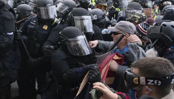 Oficiales de policía del Capitolio hacen retroceder a los manifestantes que intentan romper una puerta en Washington, Estados Unidos, el miércoles 6 de enero de 2021.  (AP/Jose Luis Magana).