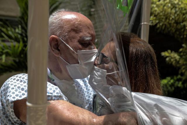 Walter Candido, de 75 años, y Marlene Amaral, de 73, se besan entre una lámina plástica usada para que pacientes y familiares puedan abrazarse en un hospital en la ciudad de Niteroi, Río de Janeiro (EFE/Antonio Lacerda).