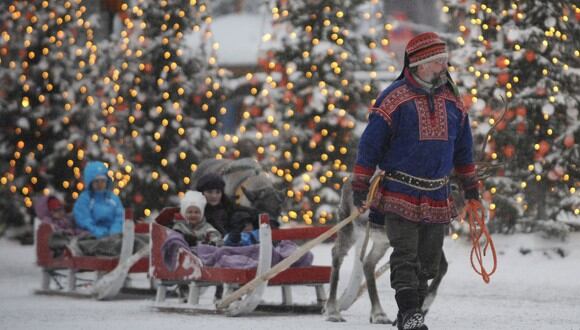Un hombre con el traje tradicional de Laplander camina con sus hijos y renos en Rovaniemi (Foto: OLIVIER MORIN / AFP)