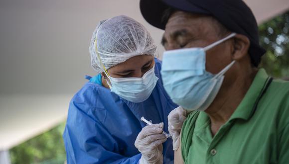 A nurse inoculates a man with the Pfizer-BioNTech vaccine against the coronavirus disease COVID-19 at a health centre set in the street in Lima, on January 11, 2022. - COVID-19 killed at least one parent or primary caregiver for nearly 100,000 children in Peru, the country with the world's highest coronavirus death rate, its government reported last week. (Photo by Ernesto BENAVIDES / AFP)