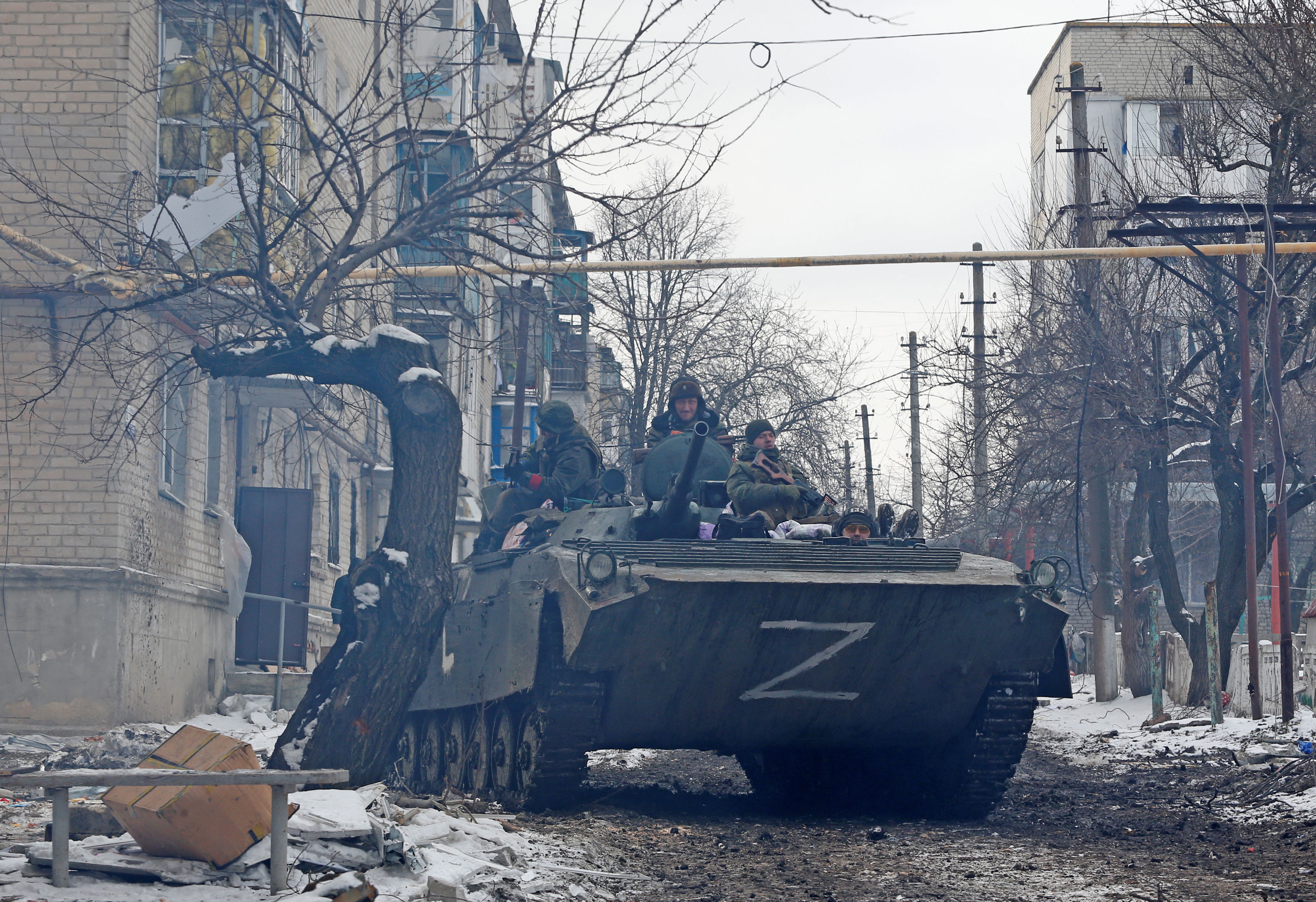 Service members of the pro-Russian troops in uniforms without insignia drive an armored car with the letters 