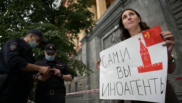 Una manifestante en agosto sostiene un cartel que dice "agentes extranjeros ustedes". (Getty Images).