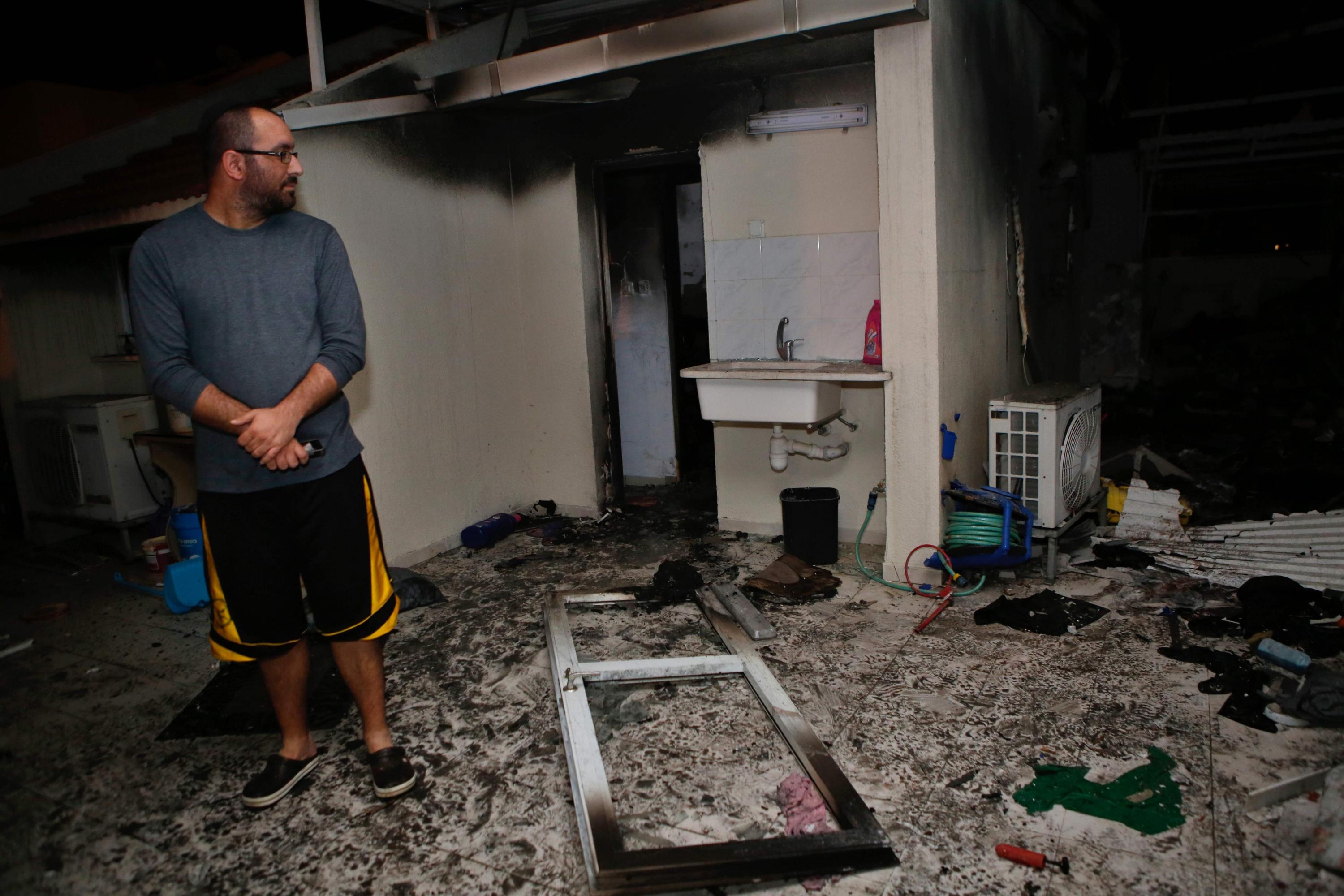 Una familia israelí inspecciona los daños provocados por un cohete que impactó en su casa en Ashkelon. (AFP).