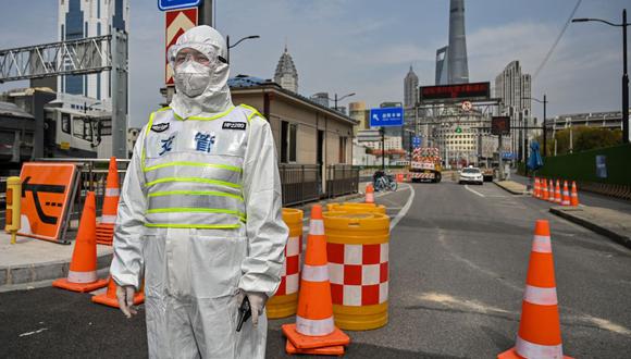 Un oficial de tránsito, con equipo de protección, controla el acceso a un túnel en dirección al distrito de Pudong, bloqueado como medida contra el coronavirus en Shanghái, China, el 28 de marzo de 2022. (Héctor RETAMAL / AFP).
