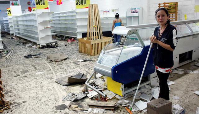 Workers clean the floor next to empty shelves and refrigerators in a supermarket after it was looted in San Cristobal, Venezuela May 17, 2017. REUTERS/Carlos Eduardo Ramirez     TPX IMAGES OF THE DAY