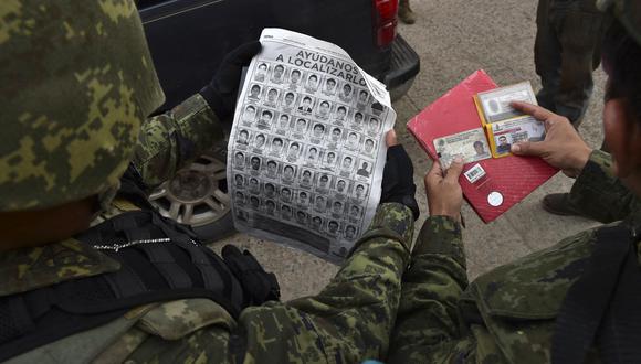 Los soldados verifican la identidad de las personas durante una operación militar de búsqueda de 43 estudiantes desaparecidos luego de enfrentamientos mortales en el estado de Guerrero, en la carretera entre Iguala y Chilpancingo, Guerrero, México. (Foto de Yuri CORTEZ / AFP)
