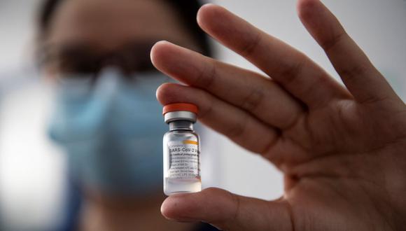 La enfermera chilena María Paz Herreros, de 32 años, quien fue la primera en inocular a un paciente contra el COVID-19 en Chile, muestra un frasco de la vacuna china Sinovac. (MARTIN BERNETTI / AFP).