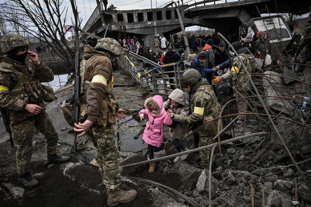 People cross a ruined bridge as they evacuate the city of Irfin, northwest of Kiev, during a severe Russian shelling on March 5, 2022.  (Aris Mesinis / AFP)