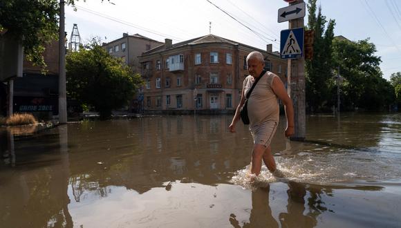 Un residente local camina por una calle inundada en Kherson el 7 de junio de 2023, luego de los daños sufridos en la represa de la central hidroeléctrica de Kakhovka. (Foto de ALEKSEY FILIPPOV / AFP)