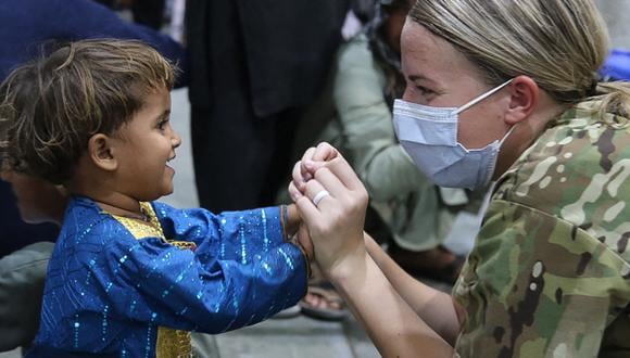 Militar estadounidense junto a un niño afgano en Kuwait. (Foto: AFP)