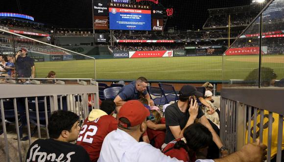 Los espectadores se ponen a cubierto durante una parada en el juego debido a un incidente cerca del estadio durante la sexta entrada de un juego de béisbol entre los Nacionales de Washington y los Padres de San Diego (Foto: AP / Nick Wass)