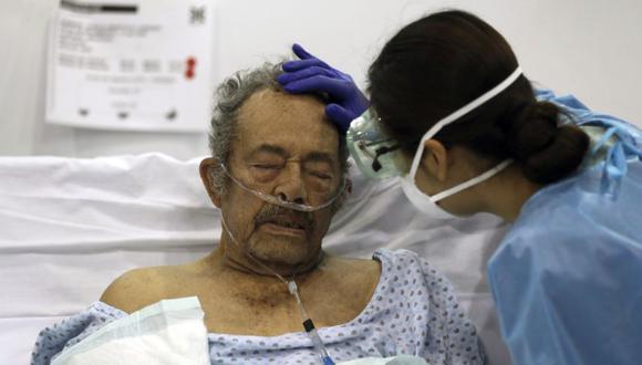 Una trabajadora de la salud acaricia la frente de un paciente con COVID-19 en un hospital de campaña construido dentro del centro de convenciones Citibanamex en la Ciudad de México. (Foto: AP / Fernando Llano, Archivo)