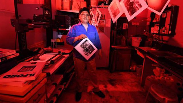 2. Vicky Luthra, un experto en revelado y positivado, posa con una fotografía en blanco y negro en el cuarto oscuro de sus estudios de impresión SV, en Nueva Delhi, el 19 de abril de 2018. (Foto: AFP)
