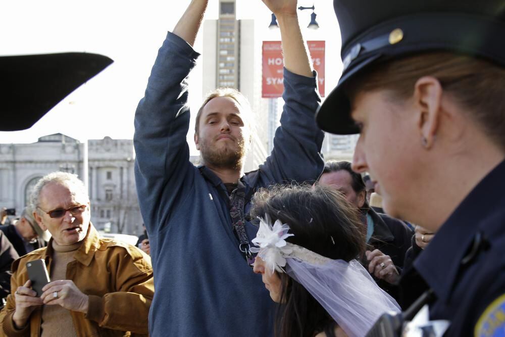 David DePape, center, films Gypsy Taub being led away by police after her nude wedding on Dec. 19, 2013, in San Francisco.  (AP Photo/Eric Risberg)