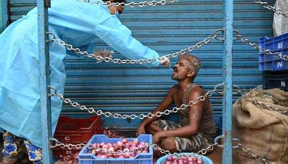 Un trabajador de la salud toma una muestra de un hisopo de un hombre para realizar una prueba del coronavirus COVID-19 en un mercado en Chennai (India), el 1 de junio de 2021. (Arun SANKAR / AFP).