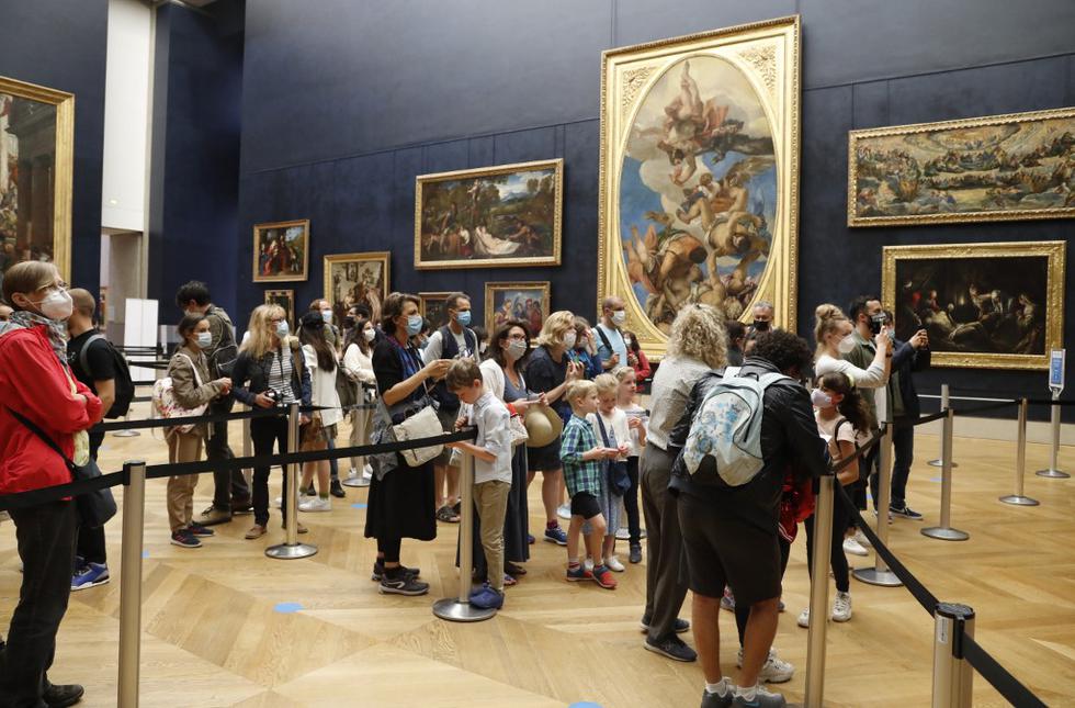 Los visitantes con máscaras faciales toman fotos frente a la obra maestra de Leonardo da Vinci "Mona Lisa", también conocida como "La Gioconda". (FRANCOIS GUILLOT / AFP)
