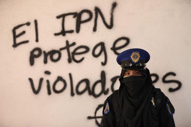 Una activista posa junto a un grafiti en el Instituto Politécnico Nacional, en Ciudad de México. (EFE/Sáshenka Guitiérrez).