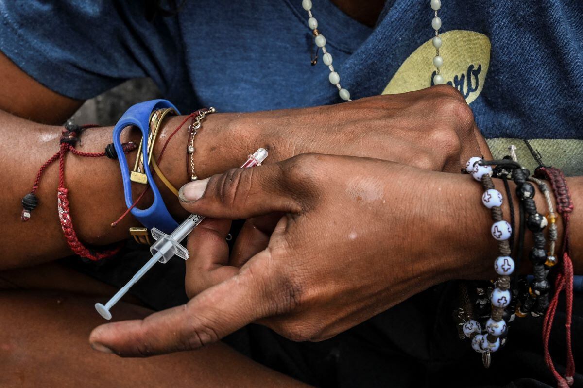 A drug addict injects heroin in the center of Medellín, Colombia, on March 19, 2022. (JOAQUIN SARMIENTO / AFP).
