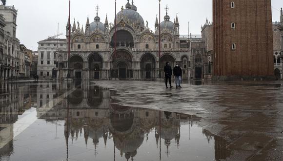 La gente camina por una plaza de San Marcos de Venecia desierta debido a la pandemia de coronavirus. (Foto de Marco Bertorello / AFP).
