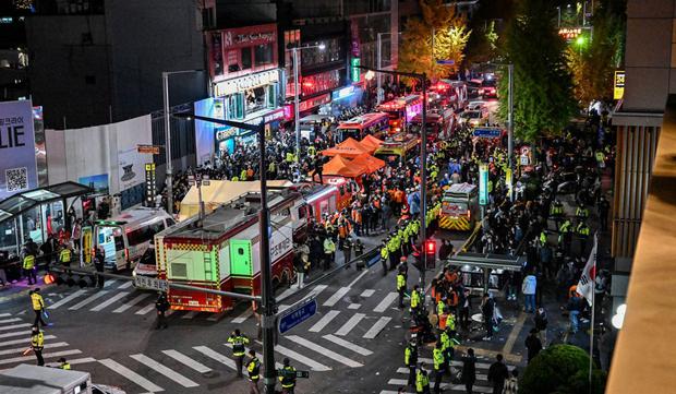 Los espectadores, la policía y los paramédicos se reúnen donde decenas de personas sufrieron un paro cardíaco, en el popular distrito de vida nocturna de Itaewon en Seúl el 30 de octubre de 2022. (Foto de JUNG YEON-JE / AFP)