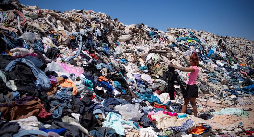Una mujer busca ropa usada en medio de toneladas desechadas en el desierto de Atacama, en Alto Hospicio, Iquique, Chile, el 26 de septiembre de 2021. (MARTIN BERNETTI / AFP).