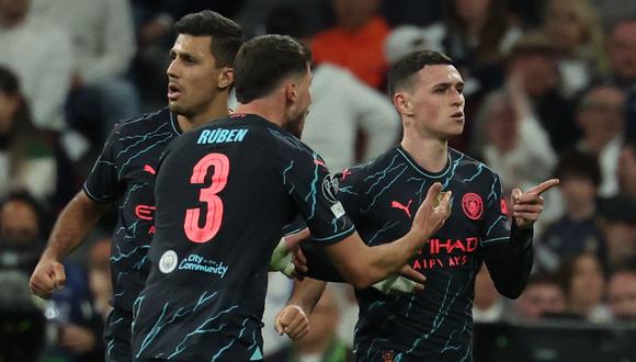 Manchester City's English midfielder #47 Phil Foden (R) celebrates with teammates after scoring his team's second goal during the UEFA Champions League quarter final first leg football match between Real Madrid CF and Manchester City at the Santiago Bernabeu stadium in Madrid on April 9, 2024. (Photo by Pierre-Philippe MARCOU / AFP)