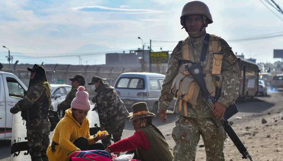 Mujeres venden comida mientras los soldados limpian los escombros dejados por los manifestantes en la carretera Arequipa-Puno, el 15 de diciembre de 2022. (DIEGO RAMOS / AFP).