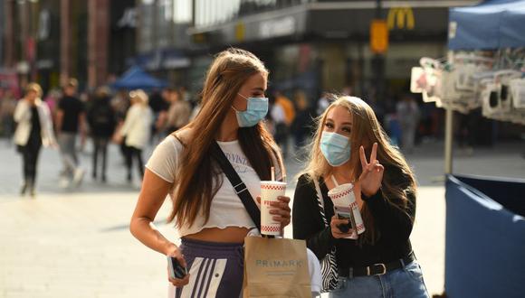 Dos mujeres que usan mascarillas protectoras contra el coronavirus caminan bajo el sol de finales del verano por el centro de la ciudad de Liverpool, en el noroeste de Inglaterra, el 18 de septiembre de 2020. (Foto de Oli SCARFF / AFP).