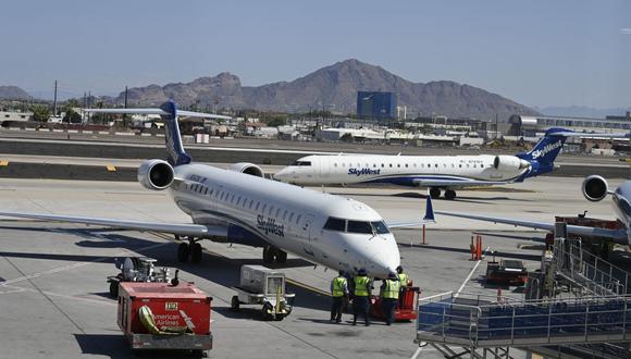 Imagen referencial. Los trabajadores de la tripulación de tierra dan servicio a un avión SkyWest estacionado en una puerta de embarque de un aeropuerto de Estados Unidos. (Daniel SLIM / AFP).
