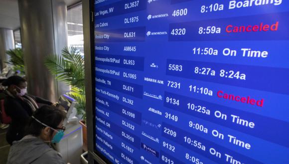 Los viajeros buscan información de vuelos en el Aeropuerto Internacional de Los Ángeles, California, el 24 de diciembre de 2021, en pleno auge del coronavirus debido a la variante ómicron. (DAVID MCNEW / AFP).