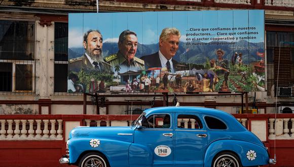 Un viejo automóvil pasa cerca de un cartel del difunto líder cubano Fidel Castro (i), el ex presidente Raúl Castro (centro) y el actual presidente Miguel Díaz-Canel (derecha) en La Habana. (Foto de YAMIL LAGE / AFP)