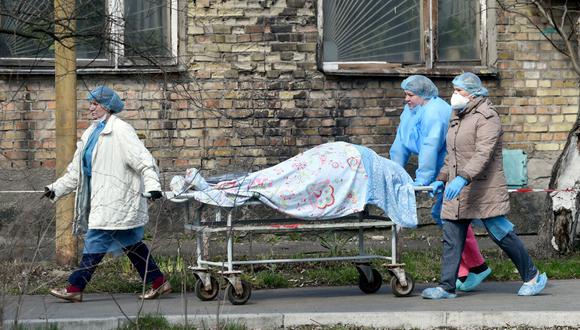 Trabajadores de la salud llevan un cuerpo en una camilla a la morgue de un hospital de Kiev, Ucrania, el 9 de abril de 2021, en plena pandemia de coronavirus. (Sergei SUPINSKY / AFP).