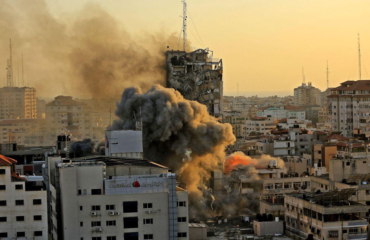 Denso humo y fuego se elevan desde la torre Al-Sharouk mientras se derrumba después de ser golpeada por un ataque aéreo israelí, en la ciudad de Gaza, el 12 de mayo de 2021. (Foto de QUSAY DAWUD / AFP).