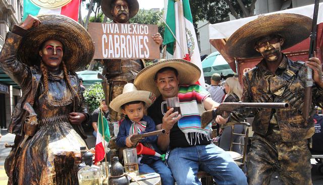 Un hombre y un niño posan para una foto con un grupo de artistas que representa mexicanos de época en las inmediaciones del Zócalo este domingo, en Ciudad de México. (Foto: EFE)