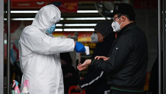 Un trabajador de un supermercado que usa traje protector toma la temperatura a un cliente en Beijing, la capital de China, país afectado por el coronavirus. (AFP).
