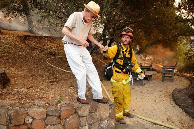 El bombero Chris Morisoli ayuda a un residente a caminar por una pendiente durante el incendio de vidrio en St. Helena, California. (Foto: REUTERS / Stephen Lam)