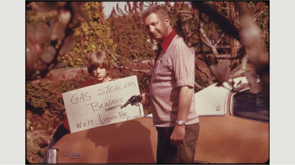 A man with a gun and a sign against fuel theft.  (US NATIONAL ARCHIVES).