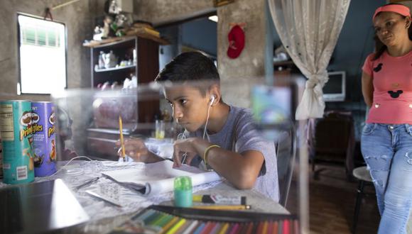 Samuel Andrés Mendoza mira una imagen de un Pokemon en su computadora antes de dibujarla en su casa en Barquisimeto, Venezuela, el martes 2 de marzo de 2021. El joven de 14 años ha estado vendiendo sus dibujos en su cuenta de Twitter para ayudar a su familia. (AP Foto/Ariana Cubillos).