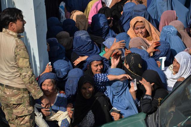 Las personas se reúnen frente a la puerta de entrada principal de un estadio de fútbol luego de una estampida que mató al menos a 11 mujeres cuando solicitaban visas para Pakistán, en Jalalabad (Afganistán). (AFP / NOORULLAH SHIRZADA).
