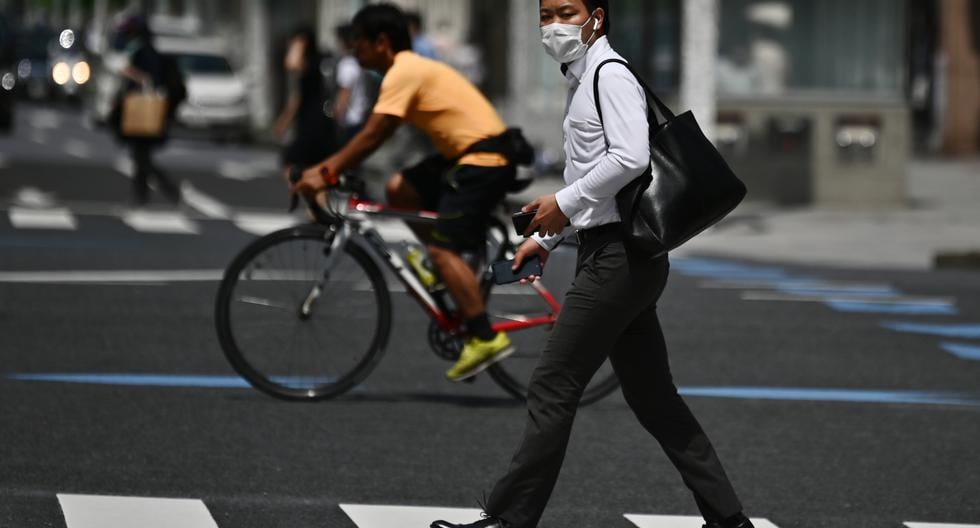 Un hombre con una máscara facial en medio del brote de coronavirus COVID-19 cruza una calle en Tokio el 13 de mayo de 2020. (Charly TRIBALLEAU / AFP)