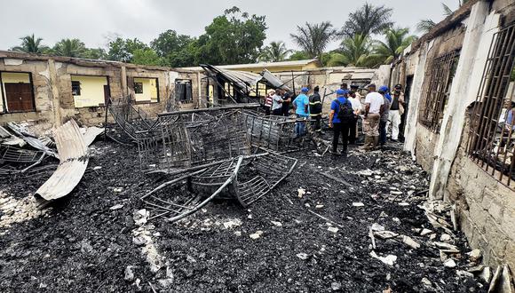 Investigadores y empleados del gobierno inspeccionan el dormitorio de la escuela donde un incendio mató al menos a 19 personas en Mahdia, Guyana, el 22 de mayo de 2023. (Foto de Keno GEORGE / AFP)